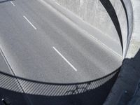 the freeway going under an overpass is empty, and a man rides his bike on it