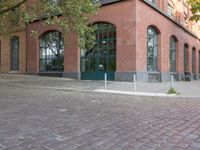 brick paved sidewalk and entrance to old red brick building with green doors in city area