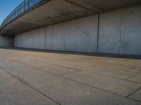 a skateboarder riding on a cement ramp next to a city street under a bridge