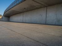 a skateboarder riding on a cement ramp next to a city street under a bridge