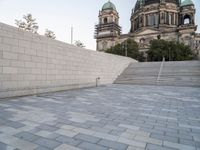 there is a skateboard that is on the steps near an elaborate building and a statue