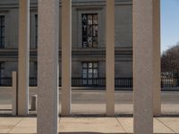 the large building has columns that are next to it, there is a sky background