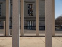 the large building has columns that are next to it, there is a sky background