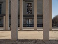 the large building has columns that are next to it, there is a sky background