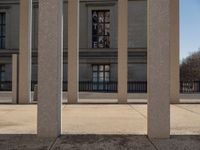 the large building has columns that are next to it, there is a sky background