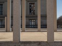 the large building has columns that are next to it, there is a sky background