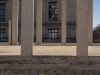 the large building has columns that are next to it, there is a sky background