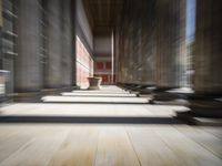 a hallway with wood floor, columns and a vase in the middle of it at the top