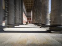 a hallway with wood floor, columns and a vase in the middle of it at the top