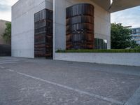 the side of a concrete building with columns of large wooden barrels in front of it