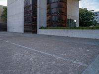 the side of a concrete building with columns of large wooden barrels in front of it