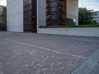 the side of a concrete building with columns of large wooden barrels in front of it