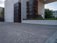 the side of a concrete building with columns of large wooden barrels in front of it