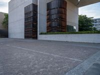 the side of a concrete building with columns of large wooden barrels in front of it