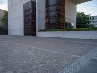 the side of a concrete building with columns of large wooden barrels in front of it