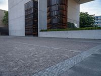 the side of a concrete building with columns of large wooden barrels in front of it