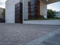 the side of a concrete building with columns of large wooden barrels in front of it