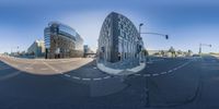 the curved glass building is on the corner at the intersection of a street, and a car is driving in