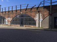 some cars parked in front of an old brick building with arches that are painted on them