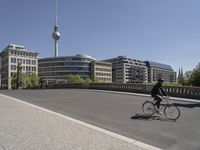 a person riding a bike down a paved walkway with two tall buildings in the background