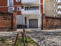 a brick walkway and some trees next to a building with windows and a bicycle rack