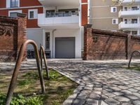 a brick walkway and some trees next to a building with windows and a bicycle rack