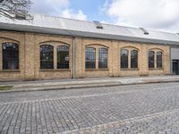 a brick building with many windows on it's sides is in the middle of an alley