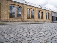 a brick building with many windows on it's sides is in the middle of an alley