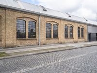 a brick building with many windows on it's sides is in the middle of an alley