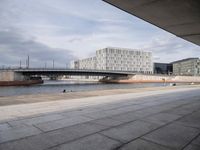 a bridge over a waterway in front of some buildings by the water with people in it