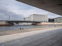 a bridge over a waterway in front of some buildings by the water with people in it