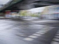 the blurry photograph is of a car driving on the street and people crossing the bridge