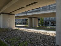 a view underneath an overpass and a sidewalk in front of it with flowers on the ground