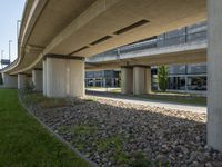 a view underneath an overpass and a sidewalk in front of it with flowers on the ground