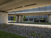 a view underneath an overpass and a sidewalk in front of it with flowers on the ground