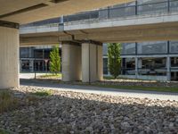 a view underneath an overpass and a sidewalk in front of it with flowers on the ground