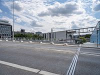 empty street near construction area with city buildings in distance and train tracks on roadway, seen in the background