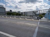 empty street near construction area with city buildings in distance and train tracks on roadway, seen in the background