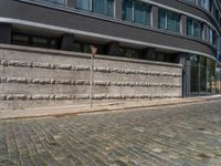 a cobblestone street next to two buildings with street signs on them, on a partly cloudy day