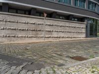 a cobblestone street next to two buildings with street signs on them, on a partly cloudy day