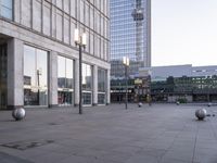 large shiny silver balls in front of a building on a city street with city buildings in the background