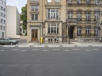 an empty building with signs on the street and people on bikes in traffic passing by