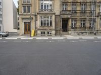 an empty building with signs on the street and people on bikes in traffic passing by