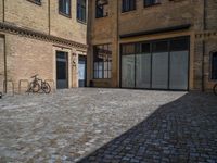 the sidewalk is paved with stones and has a bench in front of it, with no people inside