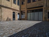 the sidewalk is paved with stones and has a bench in front of it, with no people inside