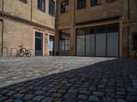 the sidewalk is paved with stones and has a bench in front of it, with no people inside