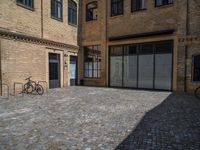 the sidewalk is paved with stones and has a bench in front of it, with no people inside