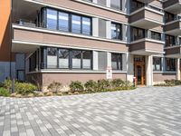 a brick driveway leading to an apartment building with a parking meter in front of it