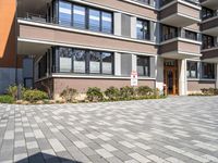 a brick driveway leading to an apartment building with a parking meter in front of it