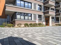 a brick driveway leading to an apartment building with a parking meter in front of it